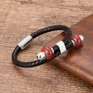 Detail van handgevlochten zwarte leren armband met rode kralen en stalen magneetsluiting