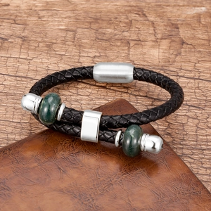 Detail van gevlochten zwarte lederen armband met groene marmeren kralen en magnetische sluiting