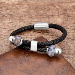 Detail van heren gevlochten zwart leren armband met blauwe steenkralen en magneetsluiting