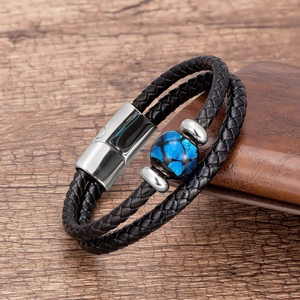 Dettaglio del bracciale a doppio strato in pelle intrecciata nera con pietra blu e fibbia