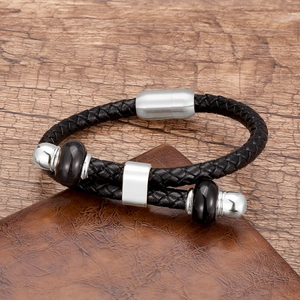 Detail van een gevlochten zwarte lederen armband met zilveren kralen en magneetsluiting