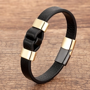 Detail of hand-woven black leather bracelet with polished gold magnetic clasp on wood