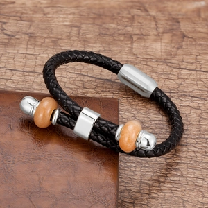 Detail van handgevlochten zwarte leren armband met kralen en roestvrijstalen magneetsluiting