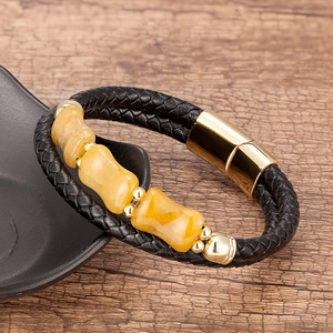 Détail du bracelet en cuir tressé noir avec pierres jaunes et fermoir magnétique doré
