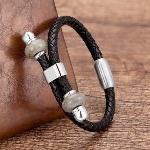 Macro-opname van zwart gevlochten leren armband met stalen sluiting en stenen kralen