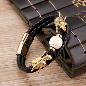 Detalle de pulsera de cuero trenzado negro con cabezas de dragón doradas y cuenta