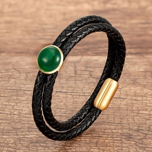 Dettaglio del bracciale in pelle intrecciata a doppio strato con pietra verde e chiusura oro