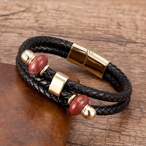 Dettaglio del bracciale in pelle intrecciata con perline rosse e chiusura magnetica