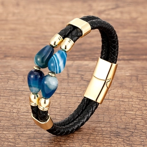 Detailed close-up of black braided leather bracelet with gold clasp and blue agate beads