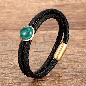 Dettaglio del bracciale doppio in pelle nera con pietra verde e chiusura magnetica dorata