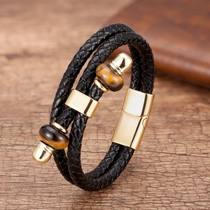 Dettaglio del bracciale in pelle nera intrecciata con occhio di tigre e chiusura dorata