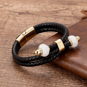 Dettaglio di bracciale in pelle nera intrecciata con perline di marmo e chiusura magnetica