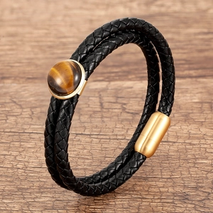 Dettaglio del bracciale doppio in pelle nera con pietra occhio di tigre e chiusura dorata