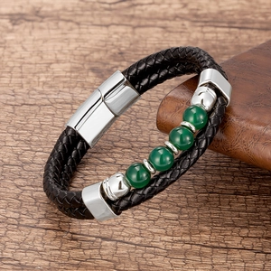 Détail d'un bracelet en cuir noir tressé avec perles vertes et fermoir en acier inoxydable
