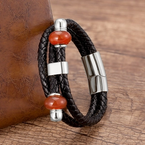 Dettaglio del bracciale in pelle nera intrecciata con perline arancioni e chiusura magnetica