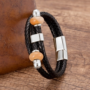 Dettaglio di bracciale da uomo in pelle intrecciata con pietre arancioni e chiusura