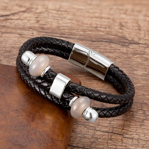 Dettaglio del bracciale da uomo a doppia fila in pelle nera intrecciata con pietre e chiusura magnetica