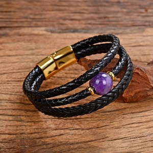 Dettaglio del bracciale multistrato in pelle nera intrecciata con pietra viola e chiusura oro