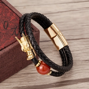 Close-up of golden dragon head charm on black braided double-layer leather bracelet