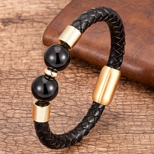 Dettaglio di un bracciale intrecciato in pelle nera da uomo con chiusura dorata e perle nere