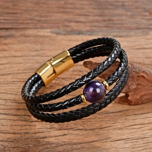 Dettaglio del bracciale in pelle intrecciata nera con pietra viola e chiusura magnetica oro