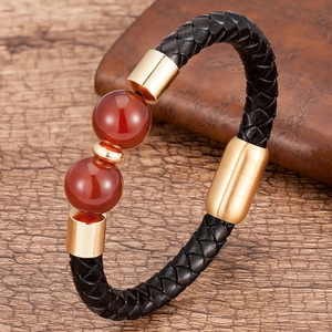Dettaglio macro del bracciale in pelle intrecciata da uomo con perle rosse e oro