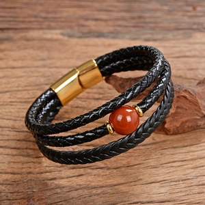 Dettaglio bracciale multistrato in pelle intrecciata nera con agata rossa e chiusura magnetica
