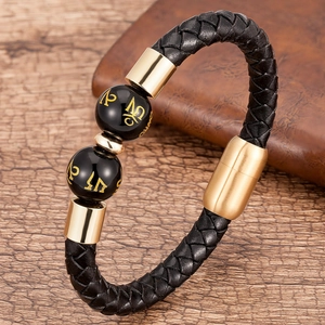 Dettaglio del bracciale in pelle nera intrecciata con perle mantra dorate su legno