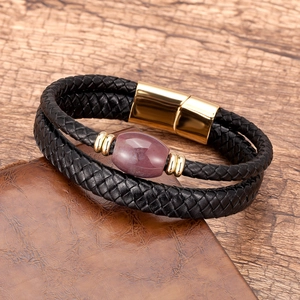 Close-up of woven black leather bracelet featuring a natural oval stone and magnetic gold clasp