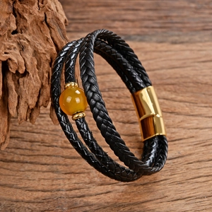 Dettaglio di bracciale multistrato in pelle nera intrecciata con perla gialla e chiusura oro