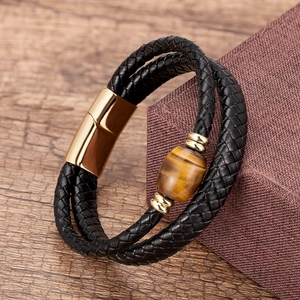 Detailed close-up of triple-layer braided leather bracelet with tiger eye stone and gold clasp