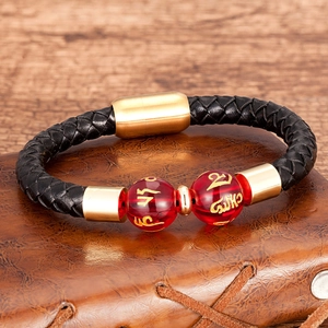 Dettaglio del bracciale da uomo in pelle con chiusura dorata e perle rosse con testo sanscrito