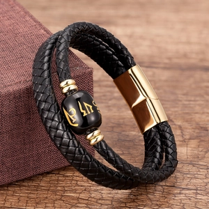 Detail of black woven leather double-wrap bracelet with golden magnetic clasp and bead