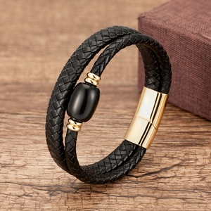 Detail of woven black leather bracelet with gold magnetic clasp and glossy black stone