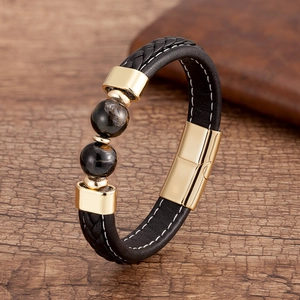 Détail d'un bracelet en cuir tressé noir avec fermoir en métal doré et perles œil de tigre