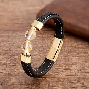 Détail du bracelet en cuir tressé noir avec fermoir doré et perles de mantra bouddhiste