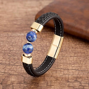 Détail d'un bracelet en cuir tressé noir avec fermoir magnétique doré et perles bleues