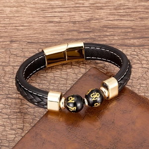 Détail du bracelet en cuir tressé noir avec fermoir magnétique doré et perles gravées