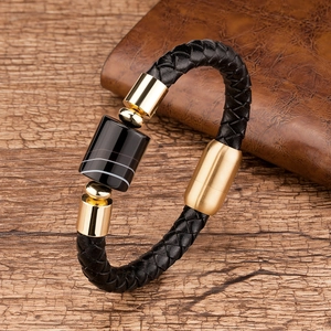 Close-up of black braided leather bracelet with gold metal clasp and striped stone bead