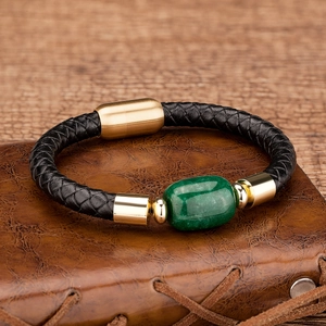 Detail of a braided leather bracelet with a green gemstone and a gold magnetic clasp