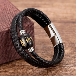 Detailed macro view of woven leather bracelet featuring a black bead with golden engraving