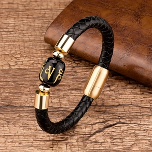Detail of woven leather bracelet with gold magnetic clasp and inscribed black bead