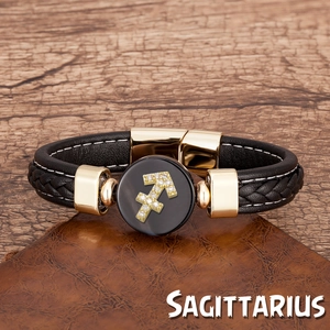 Gros plan du bracelet en cuir tressé noir avec breloque Sagittaire dorée sur bois