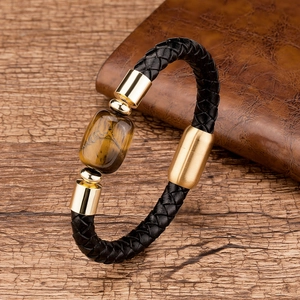 Macro detail of men's braided leather bracelet with golden tiger eye stone and polished clasp