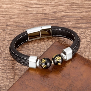 Gros plan d'un bracelet en cuir tressé noir avec des perles gravées sur un bureau