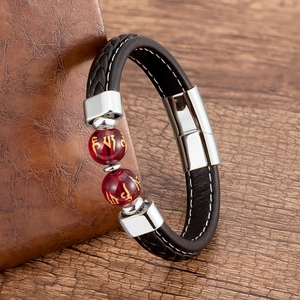 Détail du bracelet en cuir tressé noir avec perles mantra rouges et fermoir en acier
