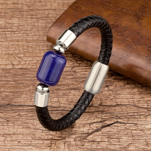 Detailed macro view of black braided leather bracelet with blue stone and steel clasp