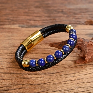 Detail of double-layer black braided leather bracelet with blue beads and gold metal clasp