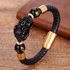 Close-up of braided leather bracelet featuring a black Pi Xiu charm and gold magnetic clasp