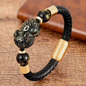 Braided leather bracelet with obsidian Pixiu charm and magnetic clasp on wooden desk